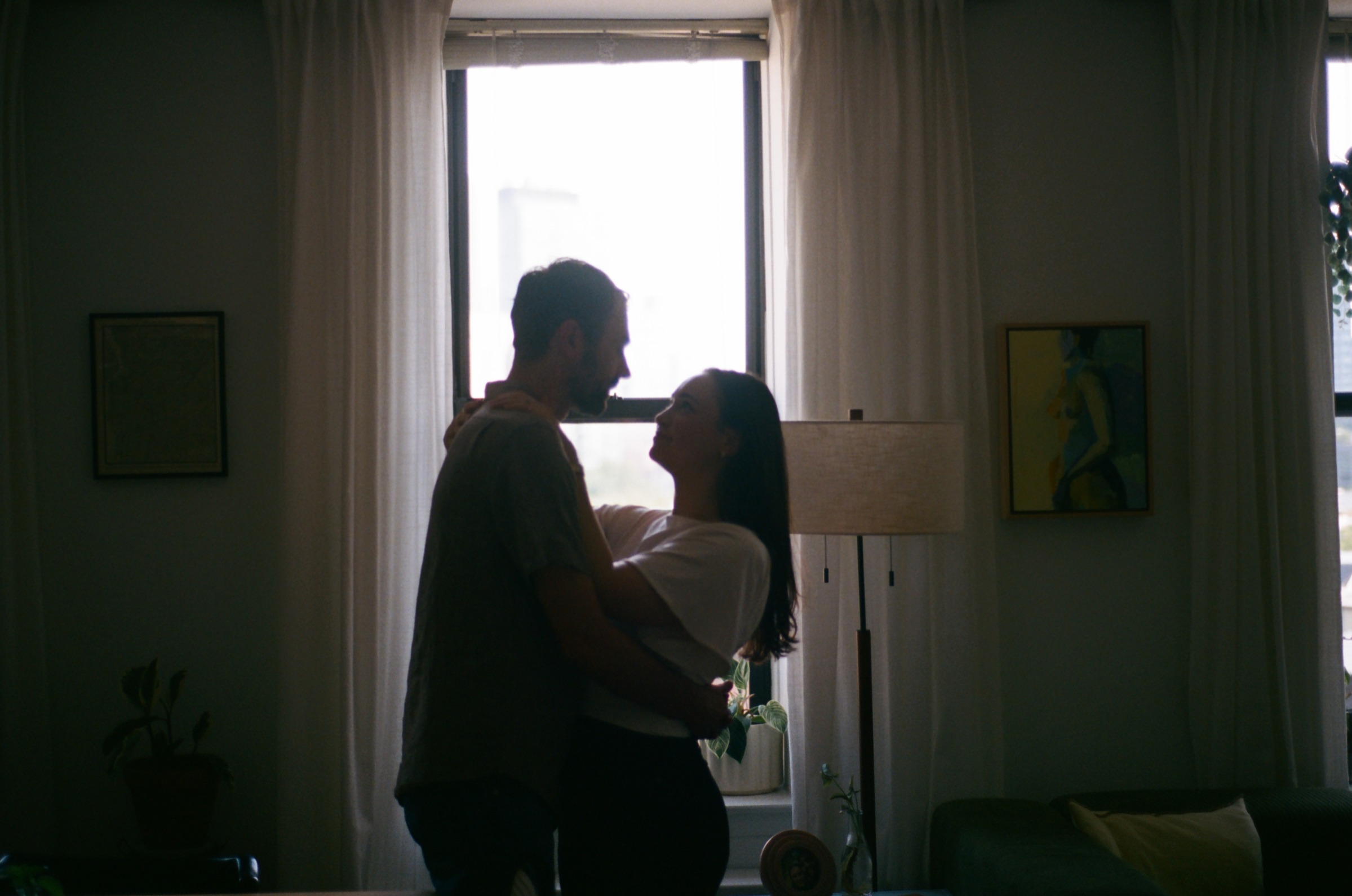 Monika and Haggai dancing together in their apartment, silhouetted against a bright window.