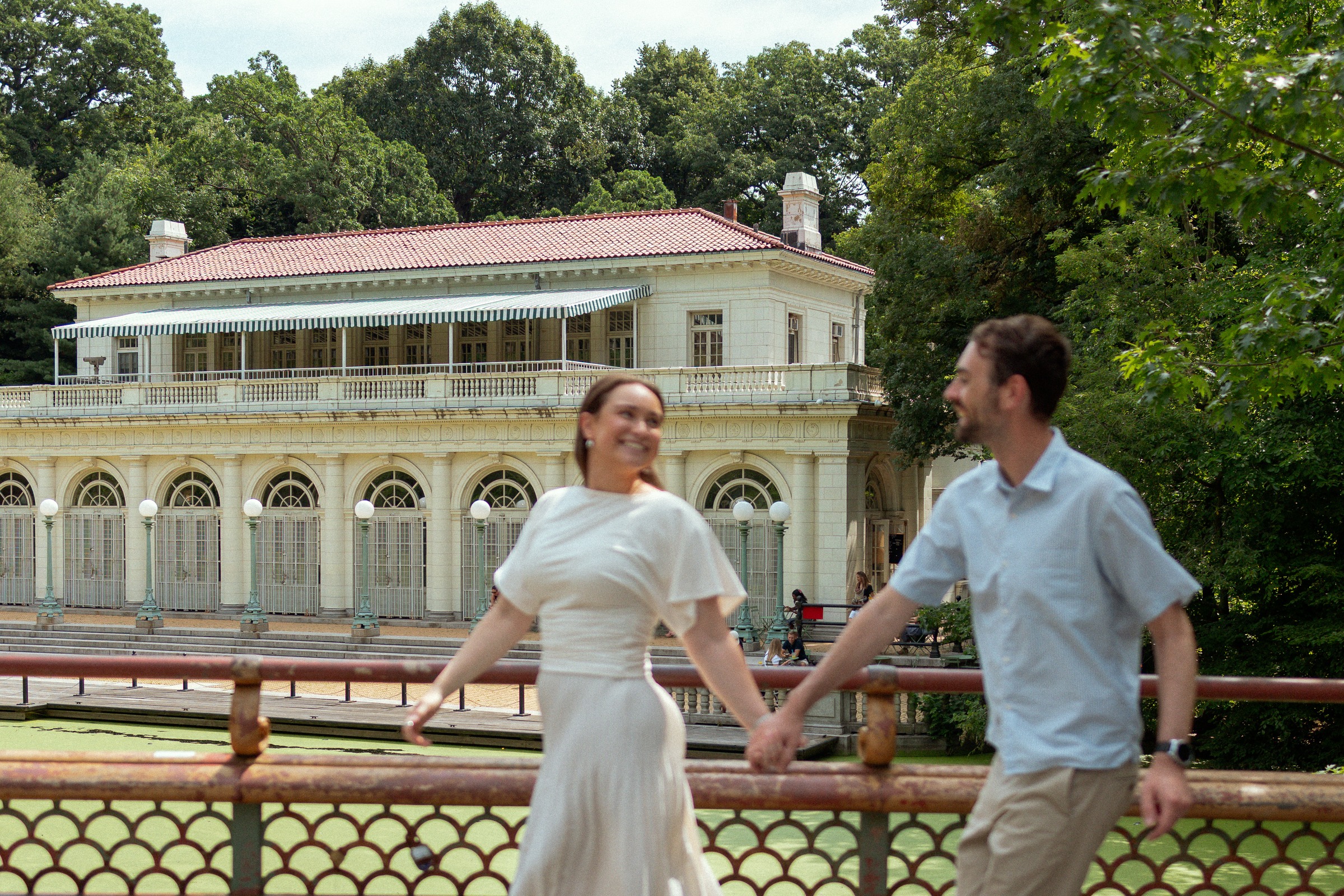 Monika and Haggai holding hands on the bridge in front of the Prospect Park boathouse.