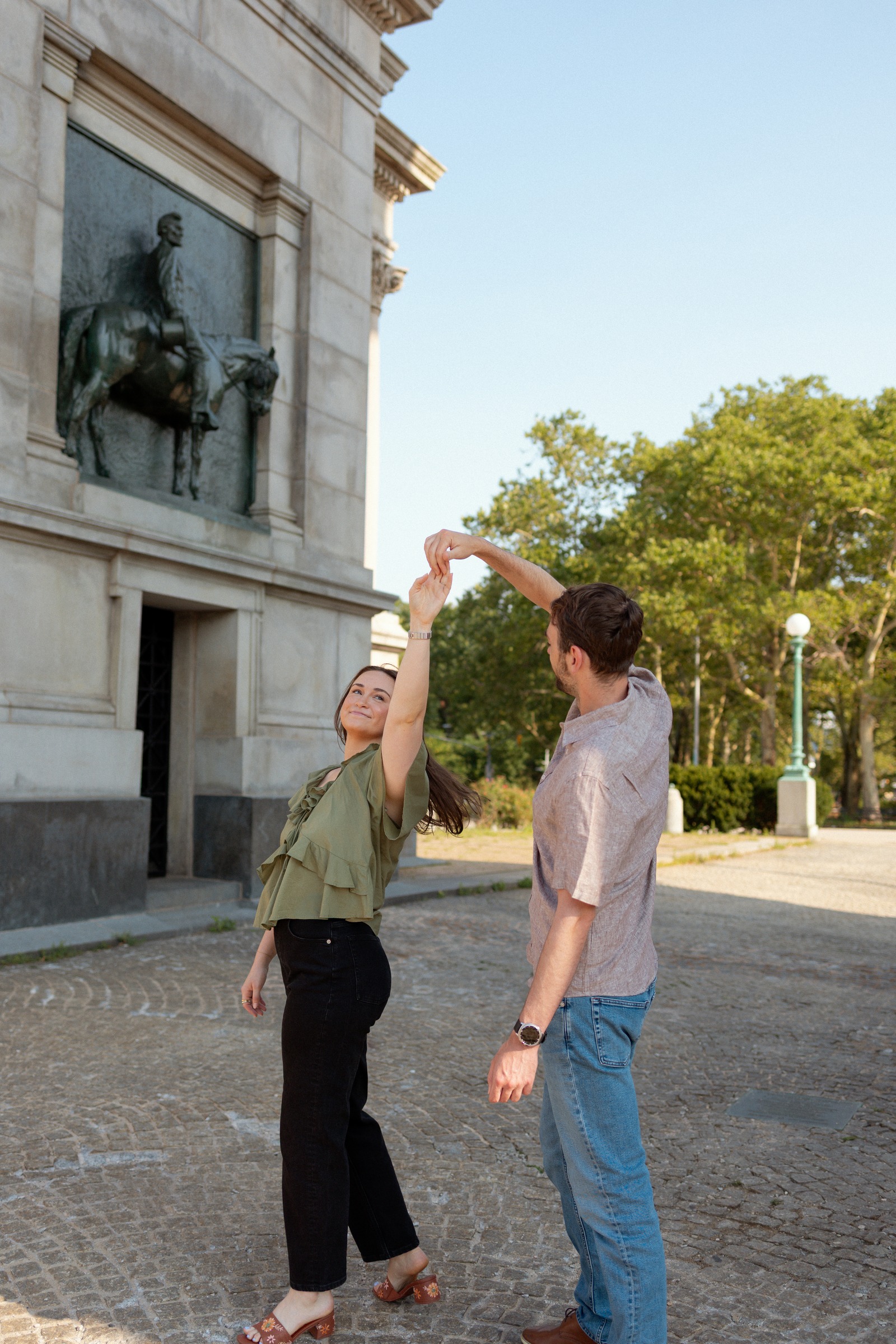 Haggai spinning Monika under his arm on the cobblestones beside the memorial arch.